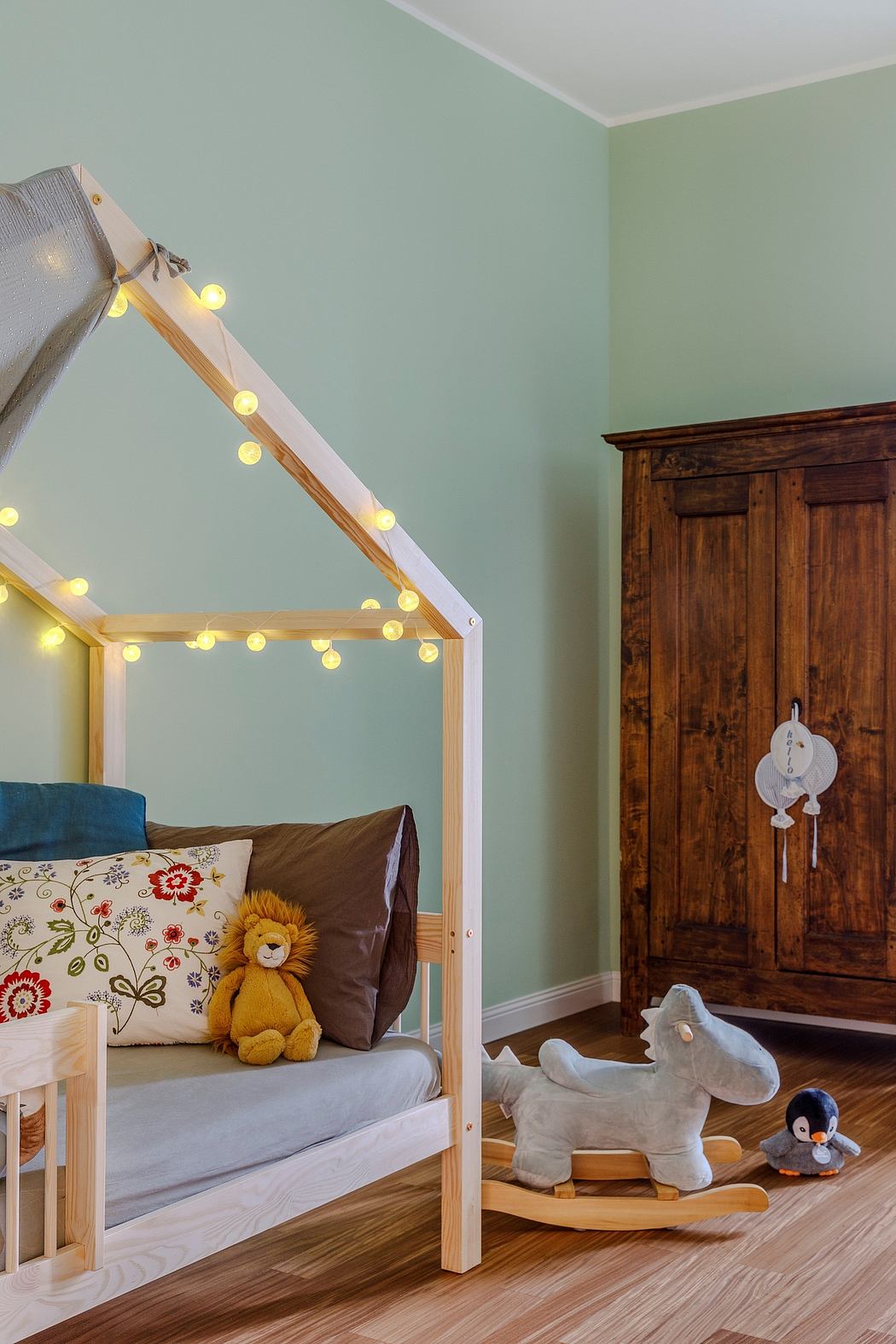 Cozy nursery with a wooden canopy bed, ornate wardrobe, and plush animal toys.