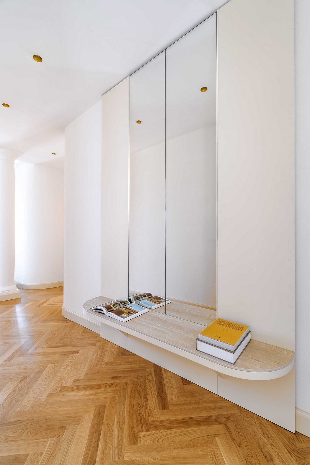 Modern minimalist entryway with built-in storage, sleek white cabinets, and parquet flooring.