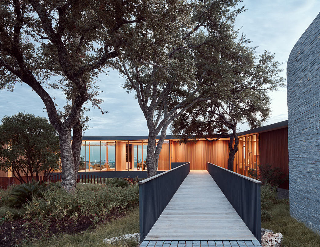 Serene wooden pavilion flanked by mature trees, leading to a tranquil outdoor space.