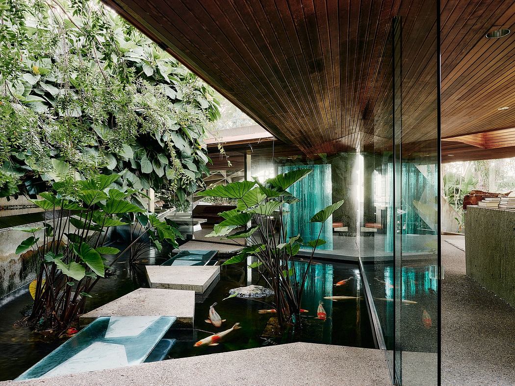 A serene indoor pond surrounded by lush greenery and a wooden ceiling structure.