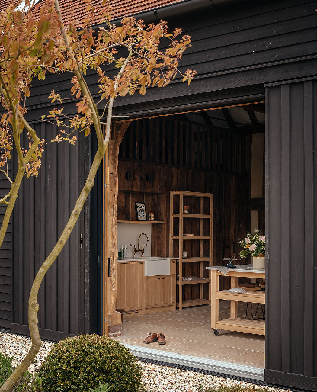 A cozy backyard studio with rustic wooden beams, a farmhouse sink, and custom shelving.