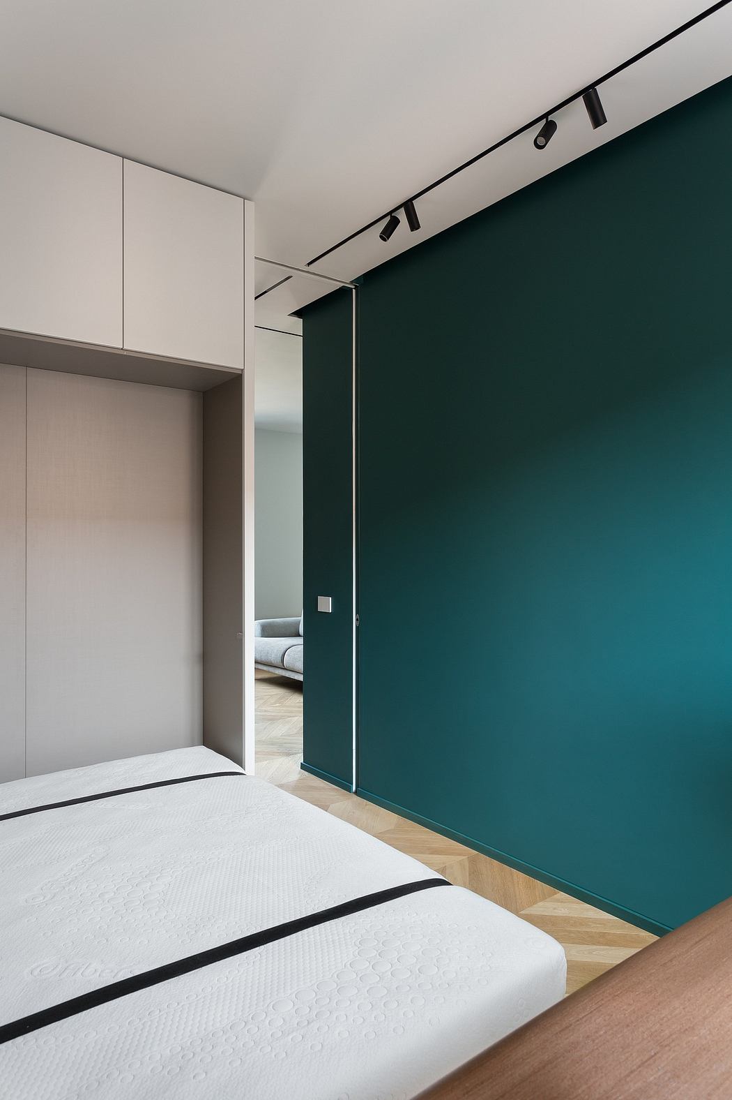 Minimalist bedroom design with white built-in cabinets, dark green accent wall, and wood floors.