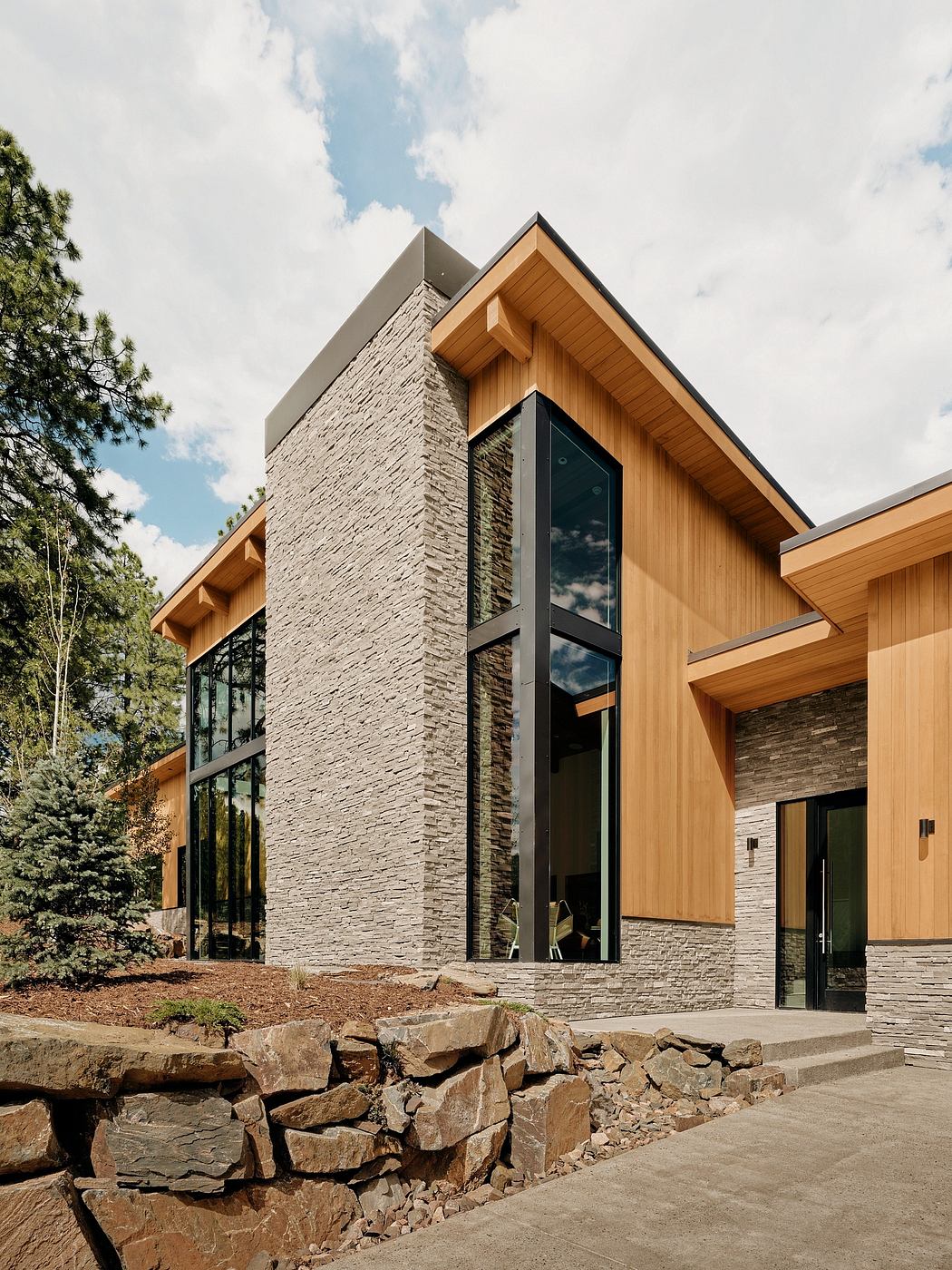 A modern home with a mix of stone, wood, and glass elements creating a striking exterior design.