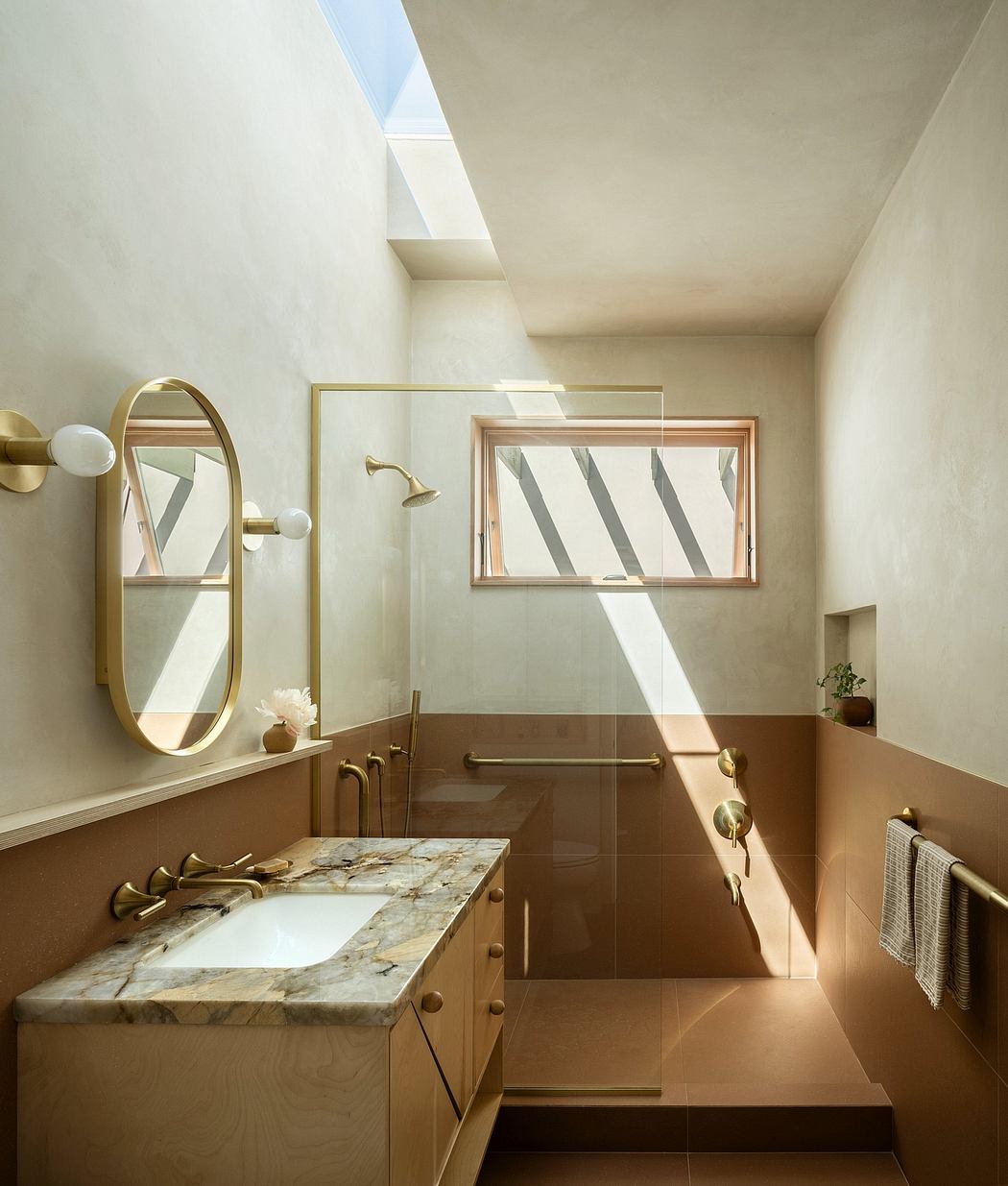 Minimalist bathroom with natural light, brass fixtures, and marble vanity.