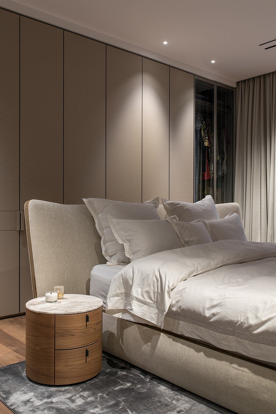 Sleek, modern bedroom with beige walls, plush bedding, and matching wood nightstands.