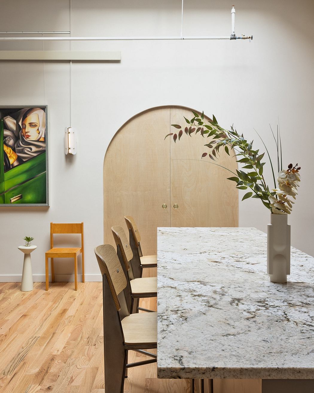 Sleek, contemporary kitchen featuring wood-paneled cabinets, marble countertops, and lush floral decor.