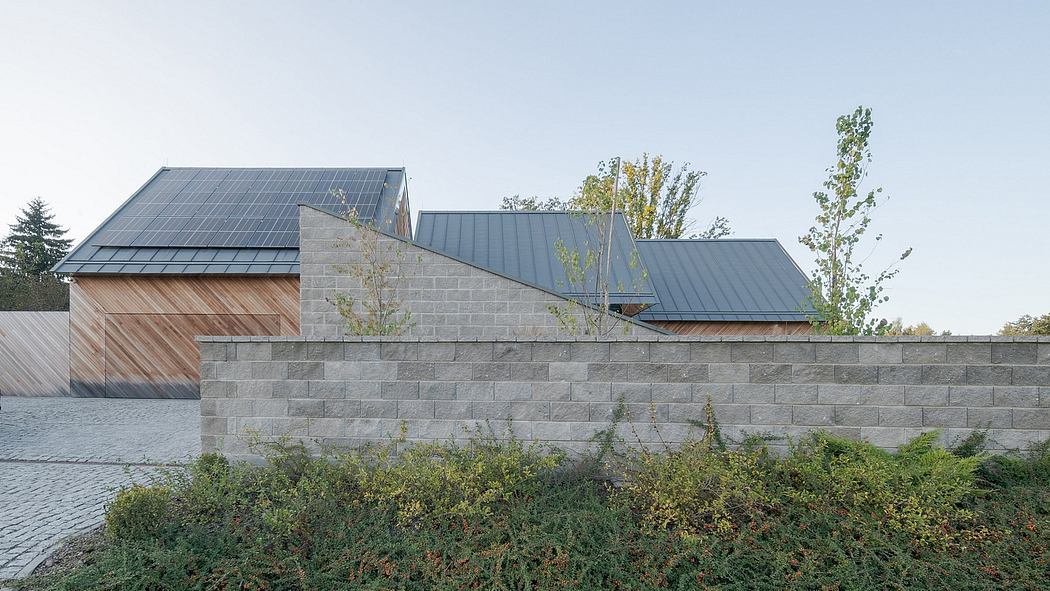 Modern architecture with grey stone walls, wooden accents, and solar panels on the roof.