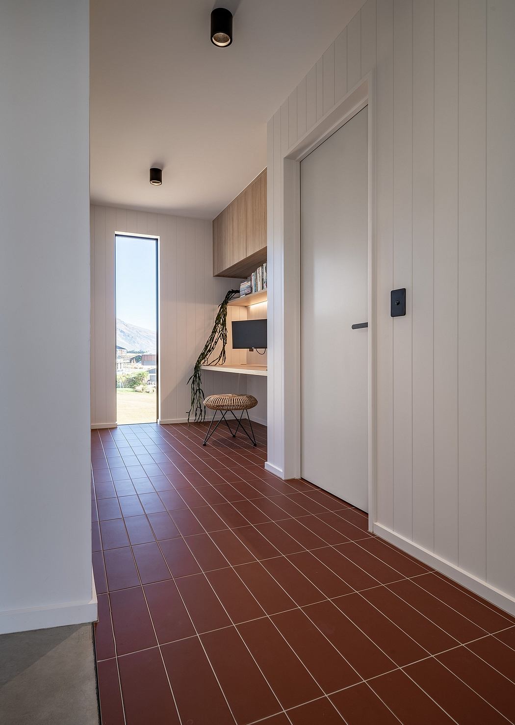 Sleek, minimalist hallway with recessed lighting, wooden shelving, and tiled flooring.