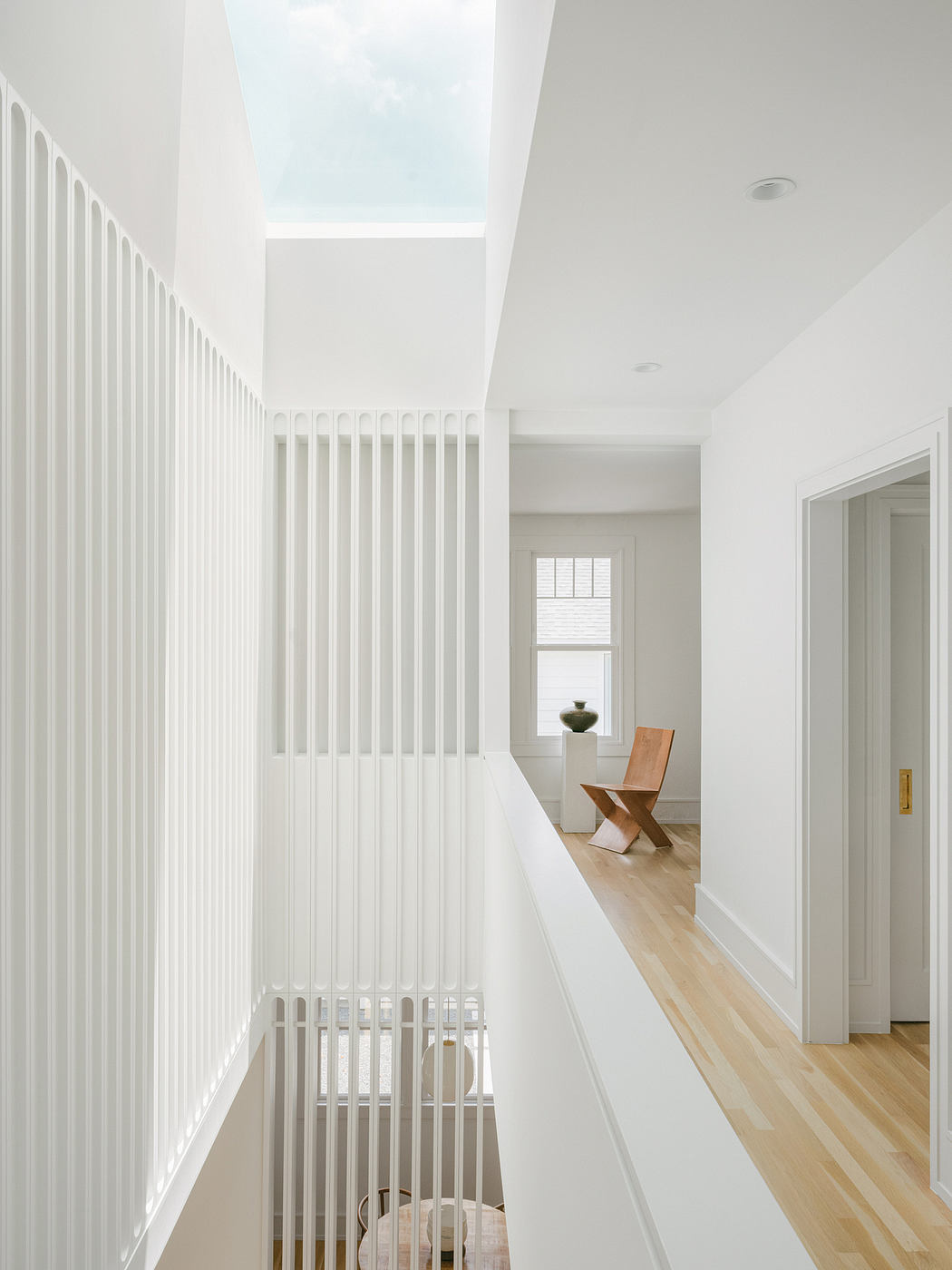 Minimalist hallway with vertical striped walls, wooden floors, and a skylight.