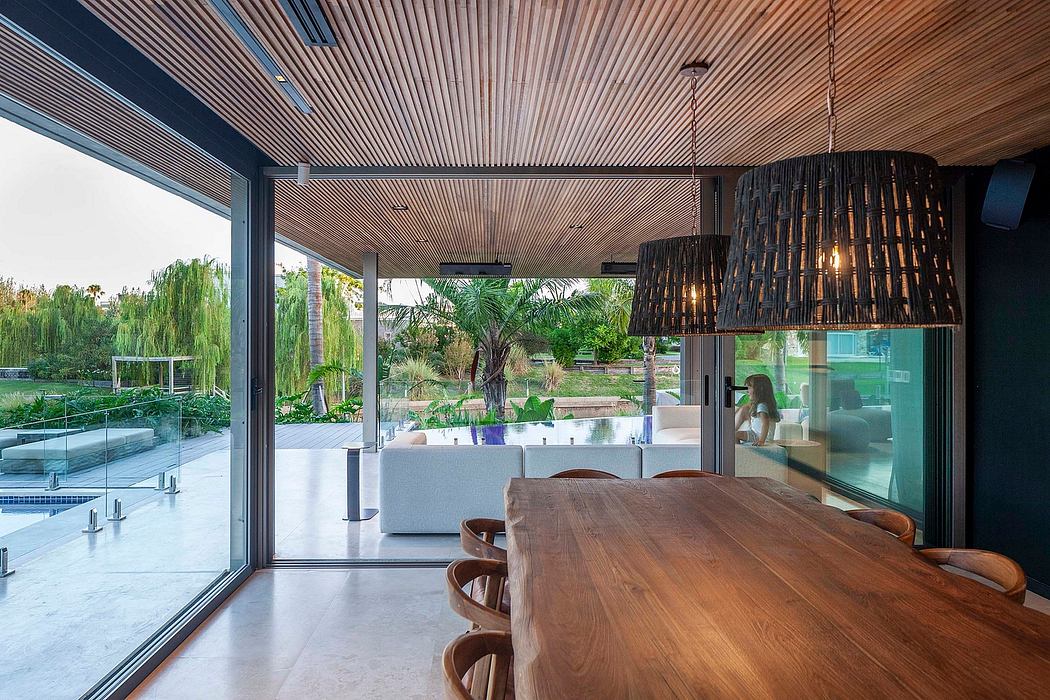Expansive glass walls, wooden ceiling, and modern furnishings in a lush outdoor setting.