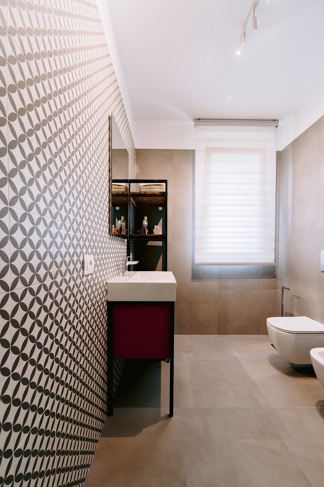 A modern bathroom with a patterned tile wall, built-in vanity, and minimalist design.