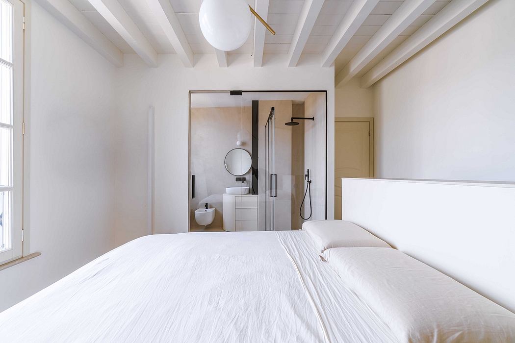 Serene bedroom with exposed beams, modern ensuite, and minimalist decor.