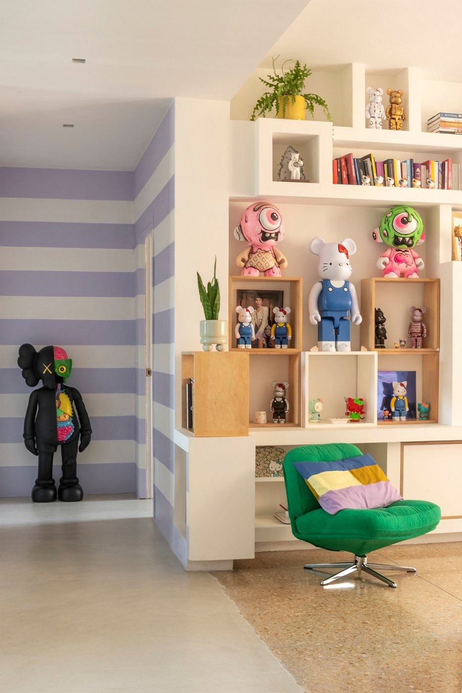 Cozy and vibrant children's room with striped walls, built-in shelves, and a stylish green chair.