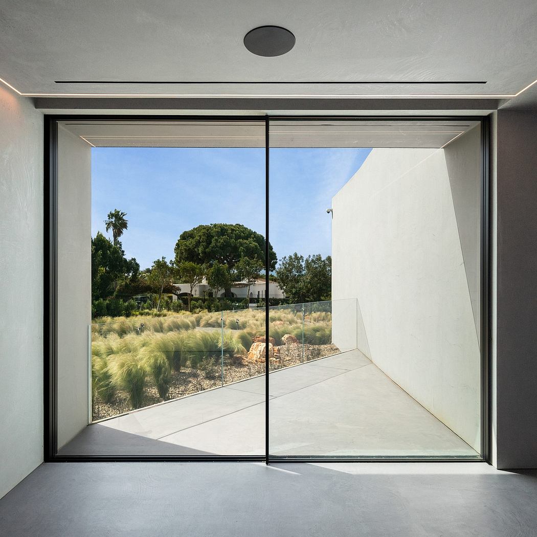 Minimalist interior space with large sliding glass doors framing a lush outdoor landscape.