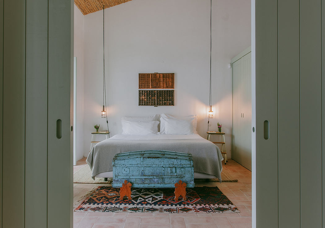 A cozy, rustic-style bedroom with a vintage trunk, patterned rug, and minimalist decor.