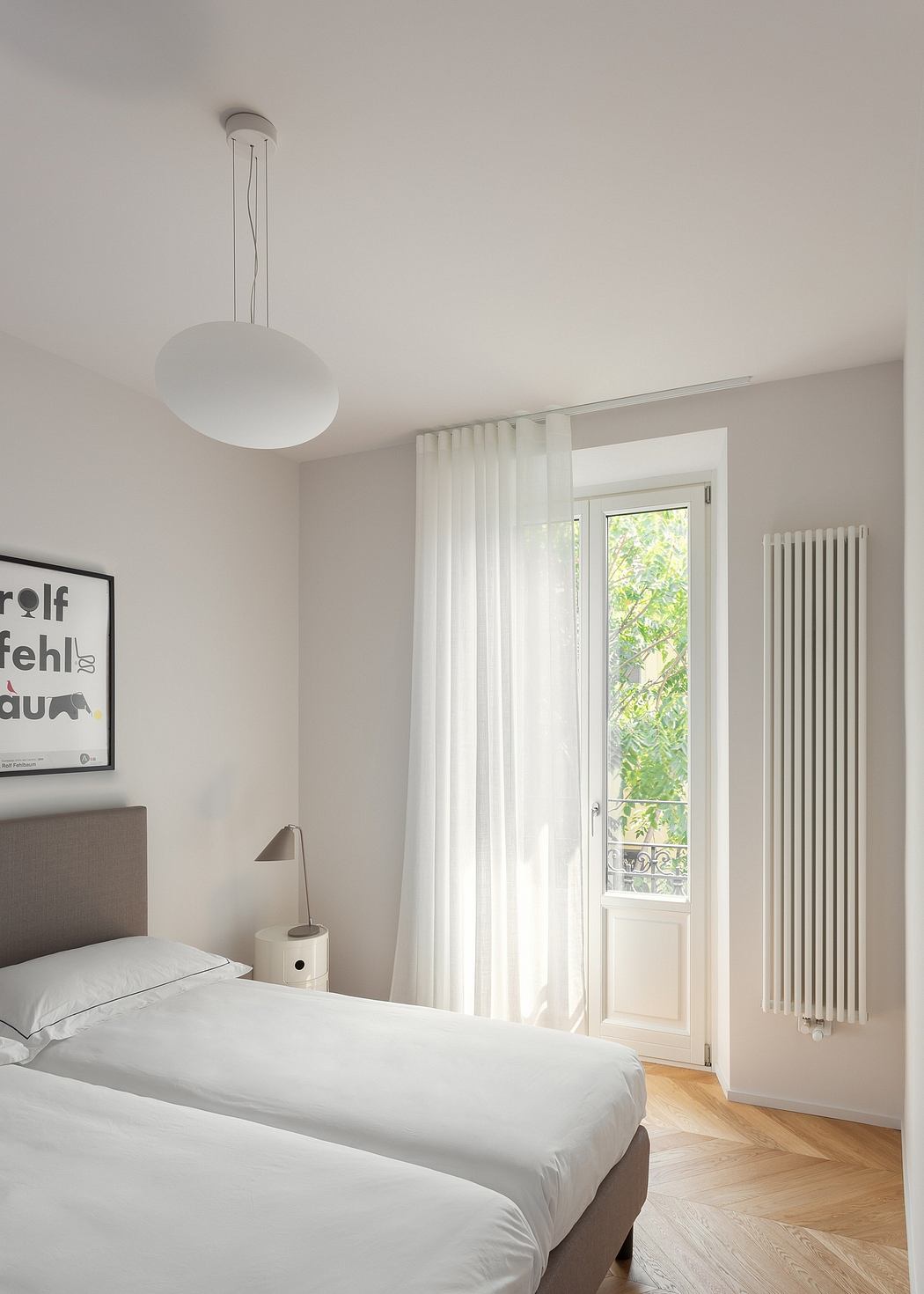 Minimalist, light-filled bedroom with white curtains, hardwood floors, and a modern pendant lamp.