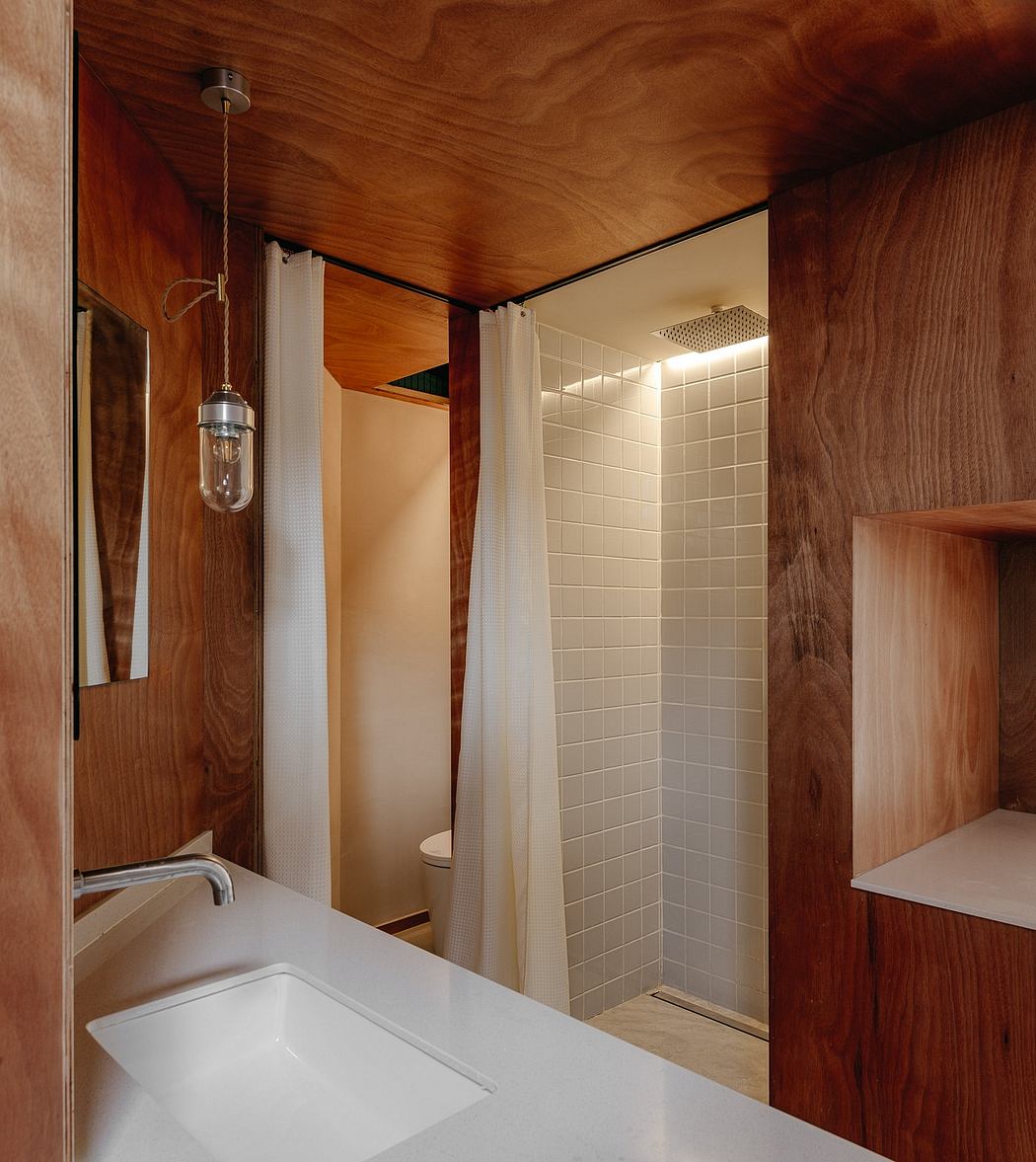 A rustic bathroom with warm wooden panels, a white tiled shower, and a minimalist sink.