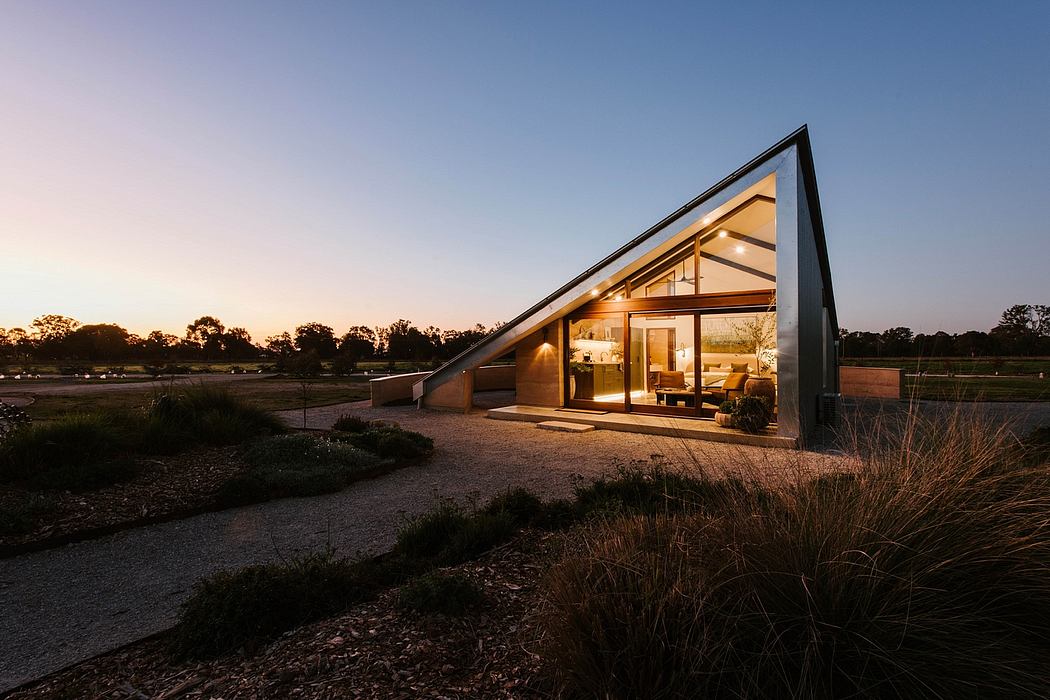 Striking A-frame structure with expansive glass walls and warm interior lighting.