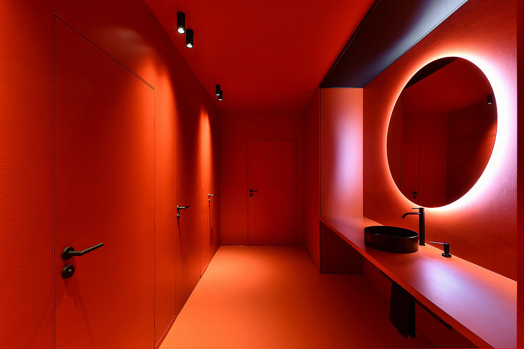 Vibrant red walls, minimalist vanity, and circular backlit mirror create a striking interior.