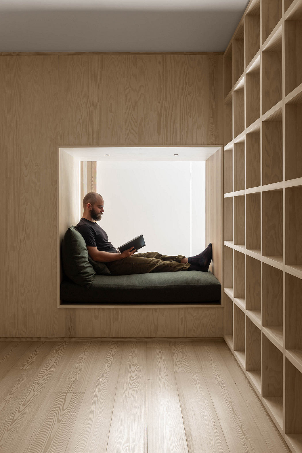 Minimalist built-in bench seating beneath built-in bookshelves in a cozy, wood-paneled nook.