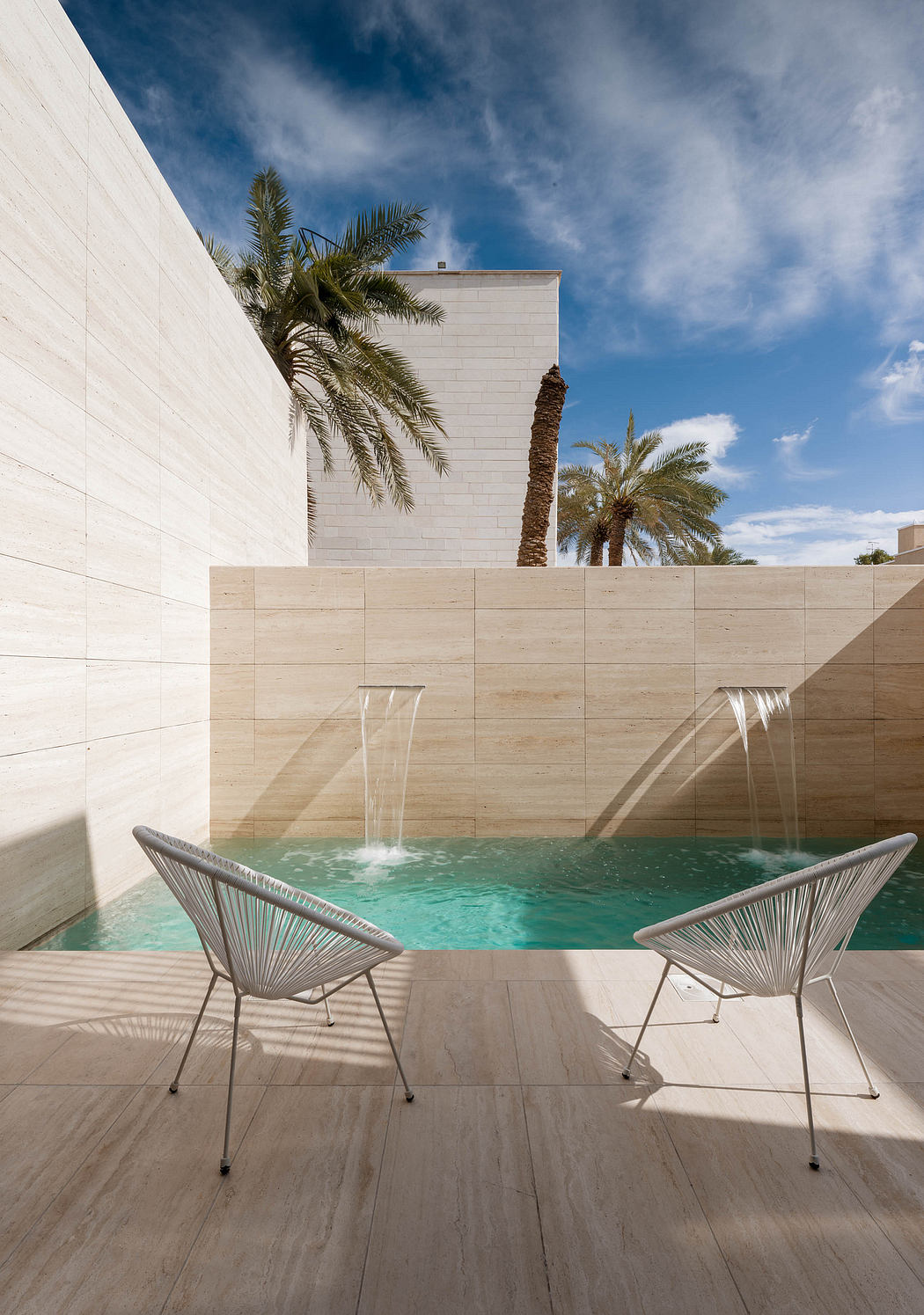 Sleek, minimalist pool with modern architectural details, palm trees, and stylish seating.