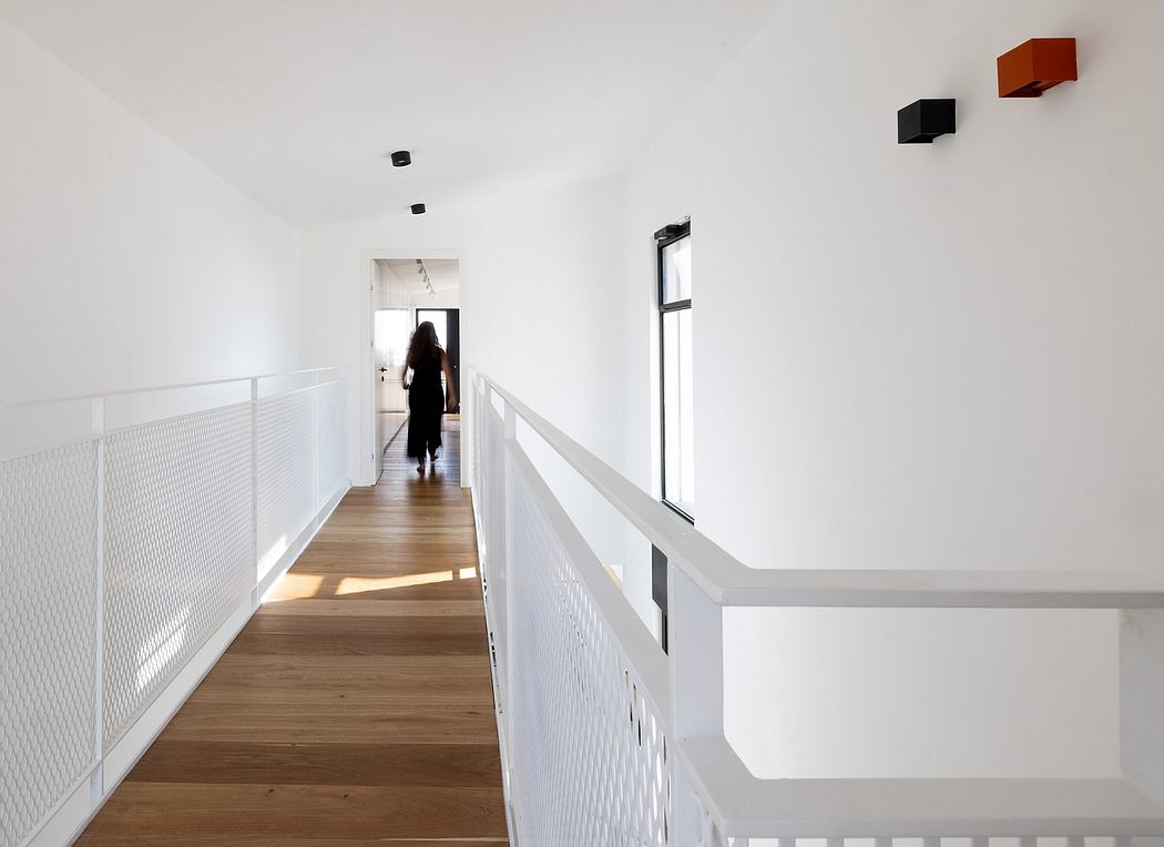 Bright, minimalist hallway with wooden floors, white railings, and rectangular wall decor.