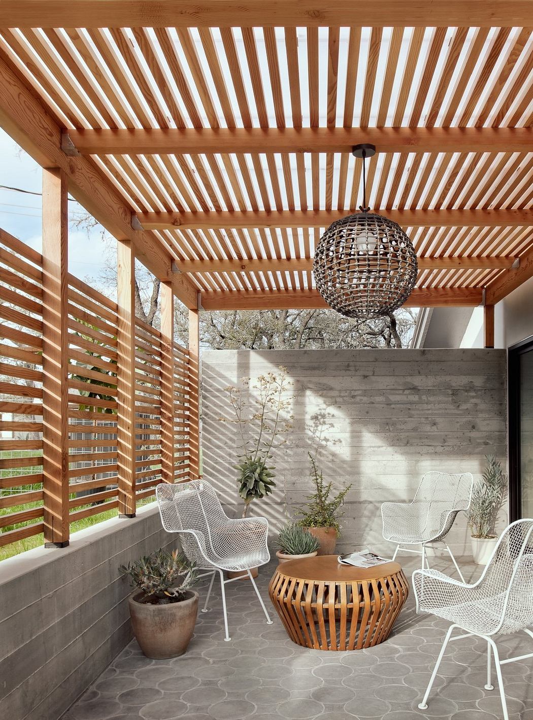 Covered patio with wooden beams, woven pendant light, and rustic furniture.