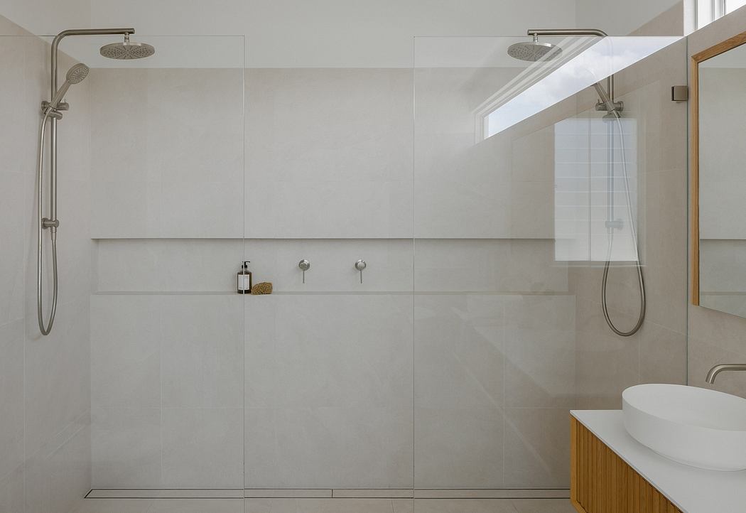 Spacious, minimalist bathroom with large, tiled shower area, modern fixtures, and natural lighting.