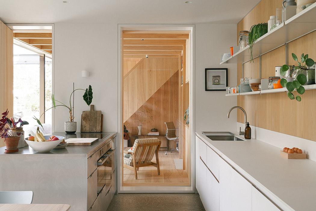 A modern kitchen with wood accents, minimalist shelving, and a view of an adjacent room.