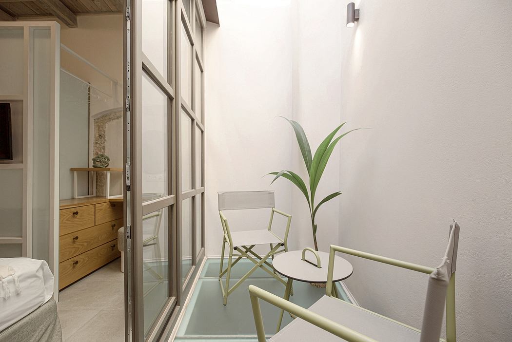 Minimalist room with glass walls, potted plant, and metal chairs on a wooden floor.