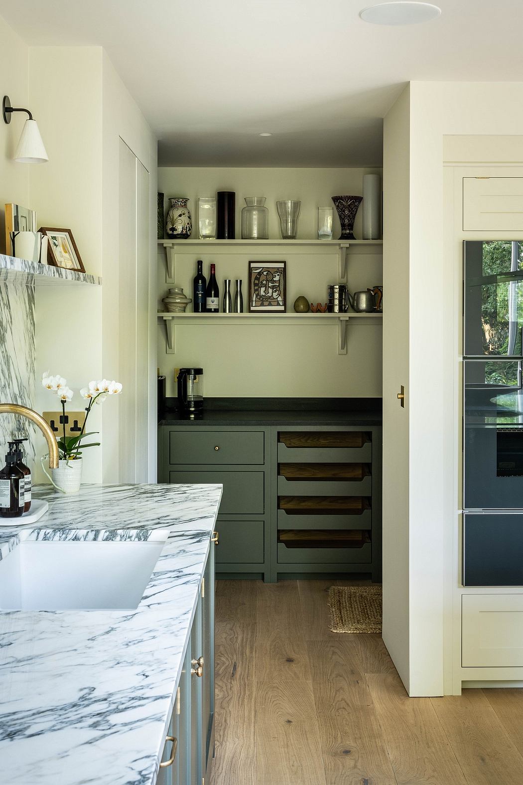 A cozy kitchen with marble countertop, built-in shelves, and wooden cabinetry.