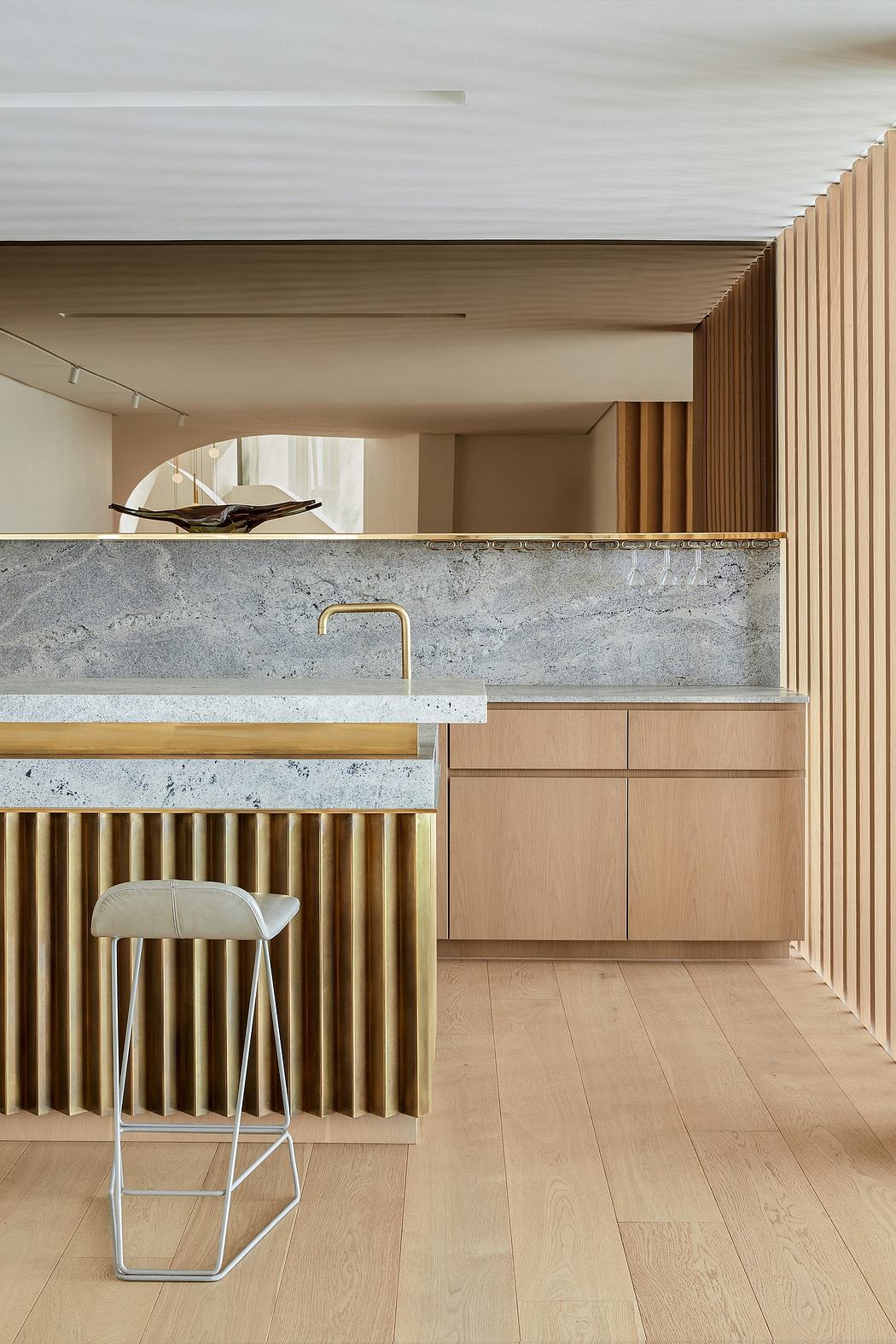Modern kitchen with wood paneling, marble countertops, and brass accents. Sleek and minimalist design.
