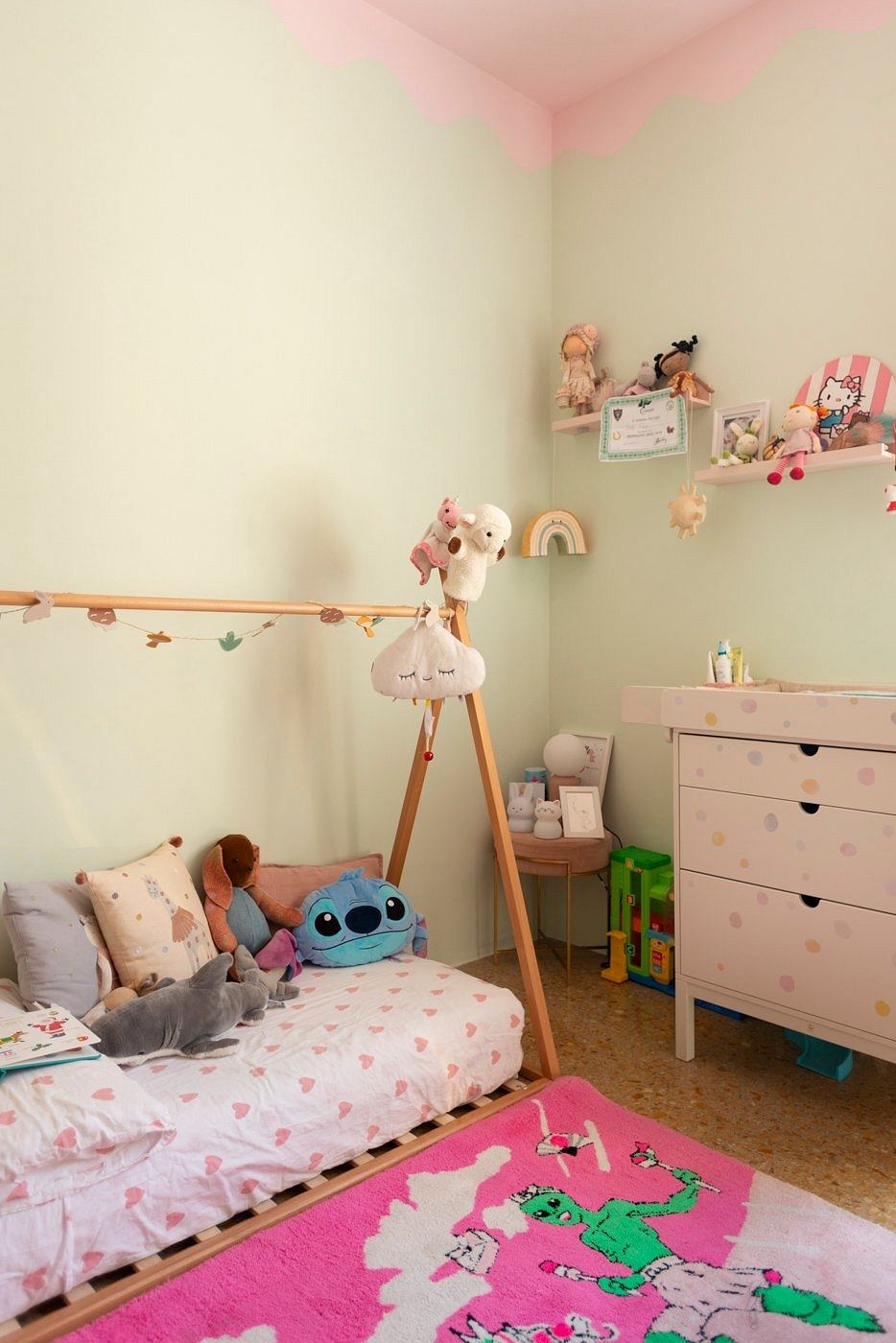 Cozy and colorful girl's bedroom with plush toys, shelving, and a patterned rug.