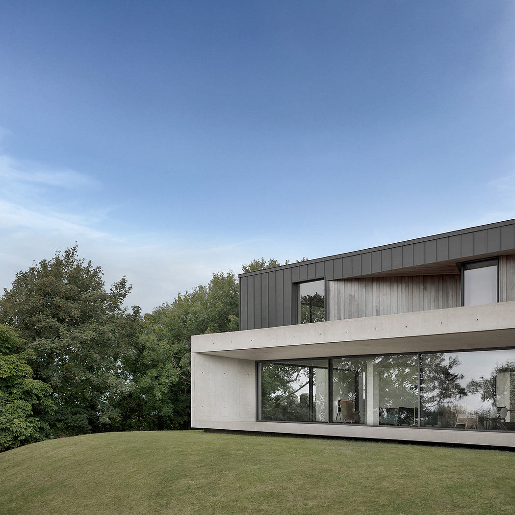 Modern minimalist house with large windows overlooking lush greenery.