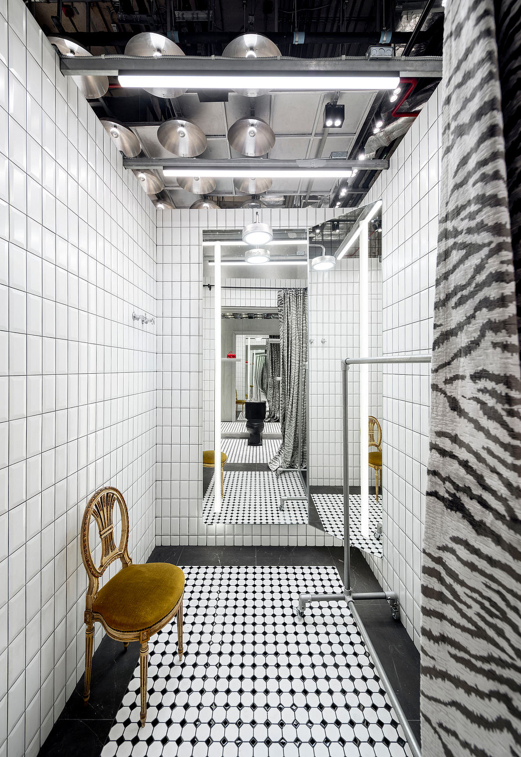 Striking black-and-white tiled bathroom with dramatic lighting and retro furnishings.