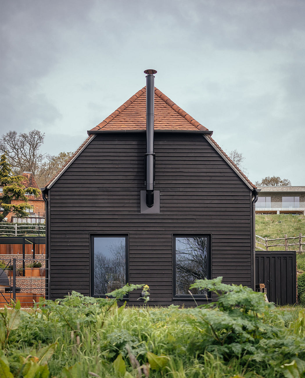A modern, black-clad building with a distinctive peaked roof and a tall chimney.