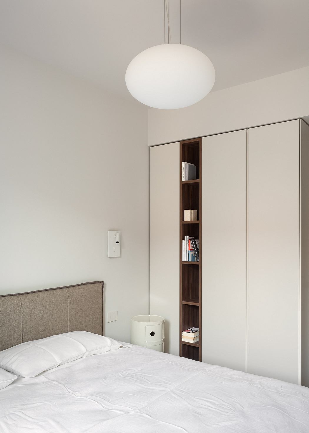 Cozy bedroom with a minimalist design, featuring a pendant light and built-in shelving.