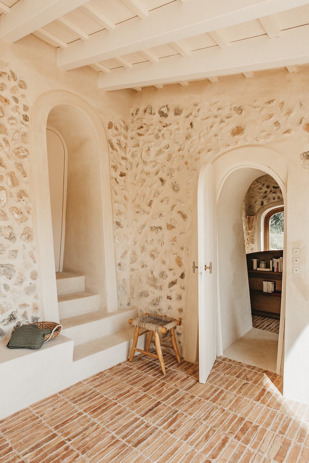 Rustic stone walls, arched doorways, and terracotta tile flooring evoke a cozy, Mediterranean vibe.