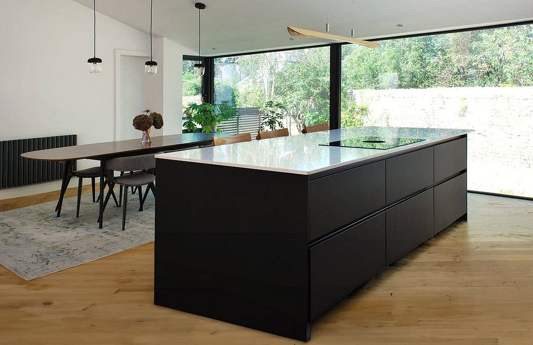 Sleek, modern kitchen with black cabinetry, stone countertops, and floor-to-ceiling windows.