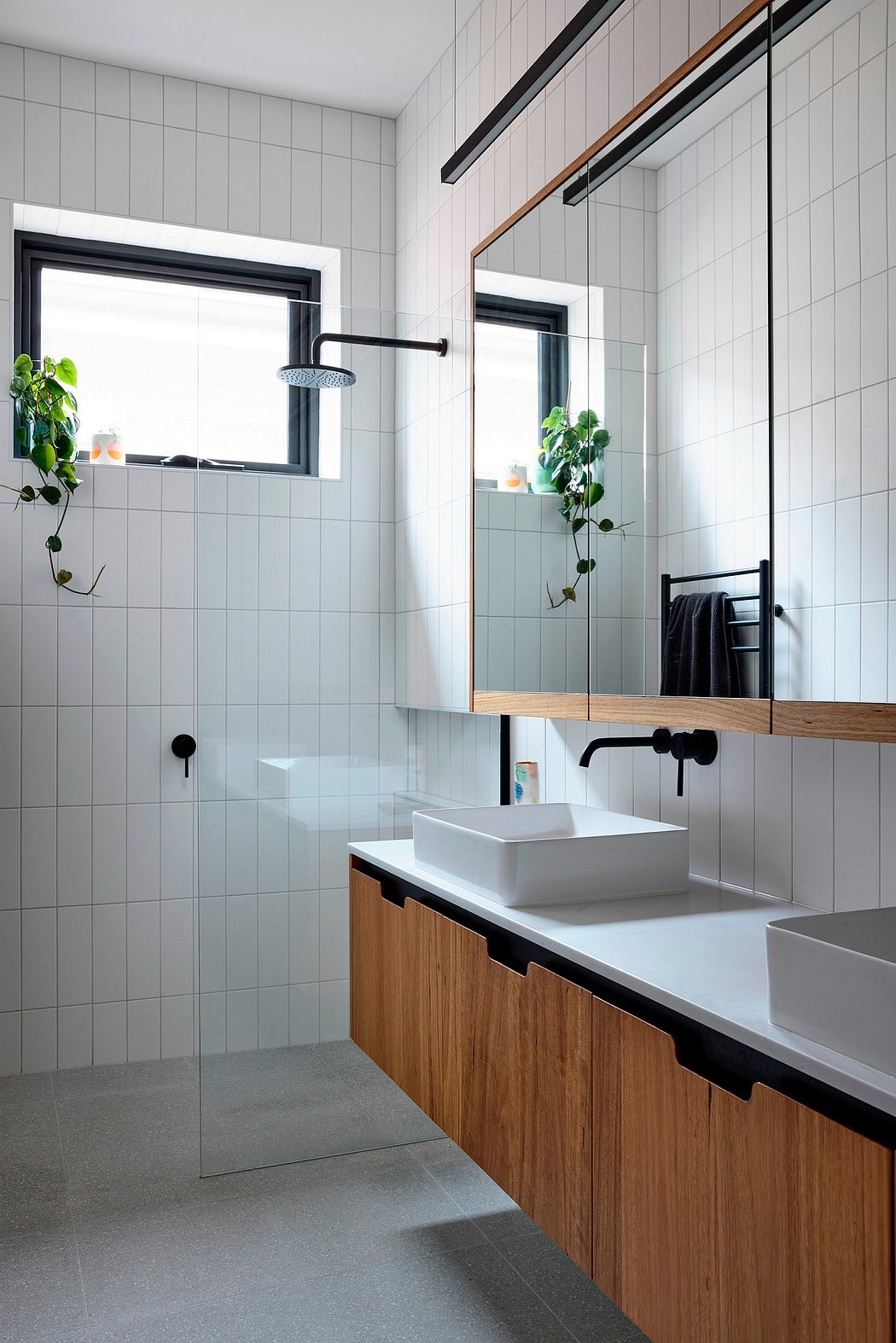 A modern bathroom with a minimalist design, featuring wood cabinetry, a vessel sink, and a large window.