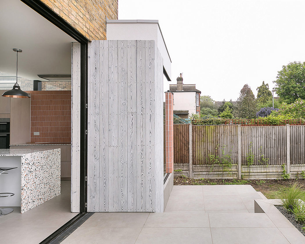 A modern, minimalist kitchen with a wood-patterned sliding door leading to a garden.