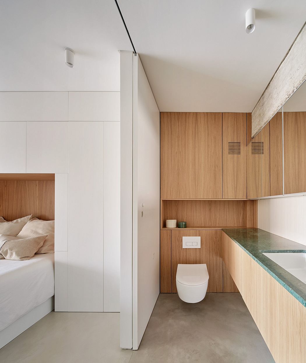 Minimalist bedroom and bathroom design featuring clean lines, wood paneling, and built-in shelving.