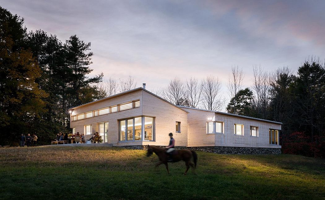 A modern, low-profile home with numerous large windows, nestled in a wooded landscape.