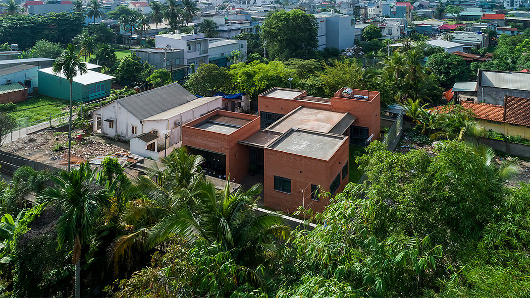 Lush tropical foliage surrounds a modern, multi-level brick building with varied roof styles.
