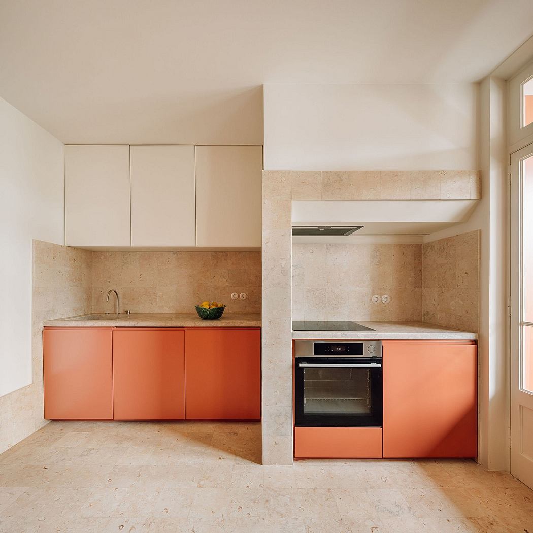 A clean, minimalist kitchen design featuring beige marble countertops and sleek, orange cabinets.