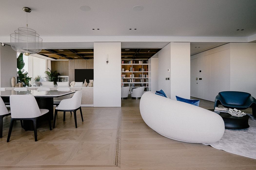 Sleek, minimalist living room with white furniture, built-in bookshelf, and pendant lighting.