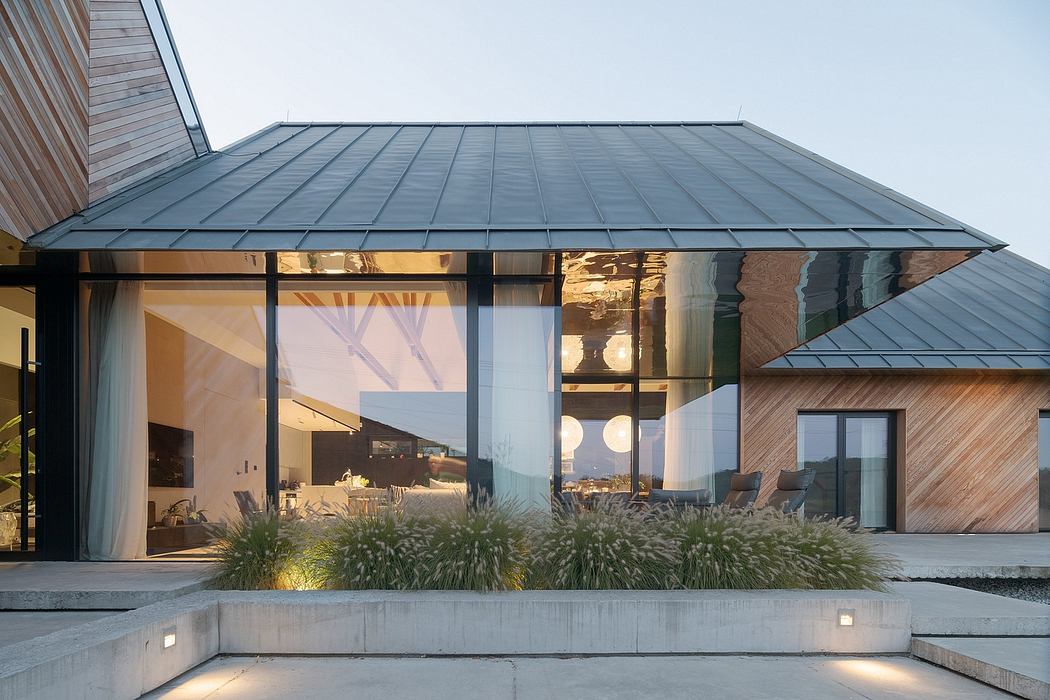 Modern architectural design with sleek metal roof, glass walls, and outdoor seating area.