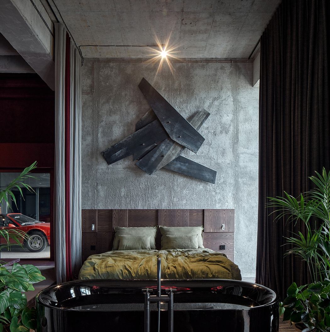 Striking concrete wall features dynamic sculpture. Warm wooden headboard contrasts with sleek black tub.