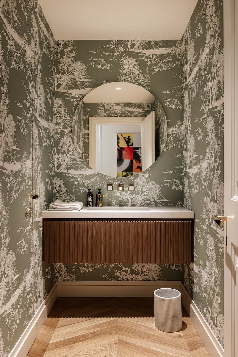 Striking botanical wallpaper creates a distinctive bathroom design, with a sleek vanity and mirror.