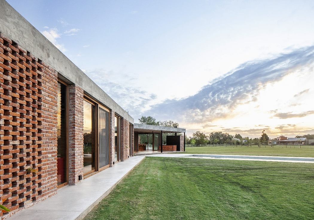 Striking brick facade, expansive glass doors, and lush grassy lawn create a tranquil scene.